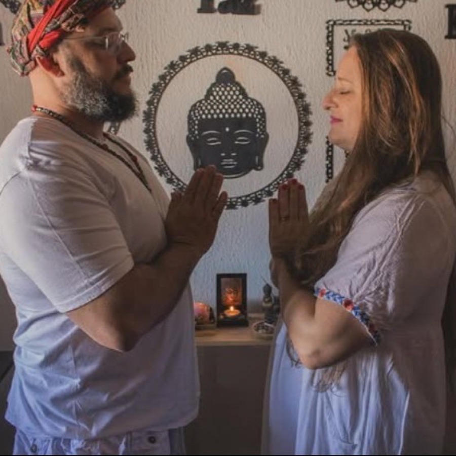 Amely e Gustavo em oração diante de uma imagem de Buda