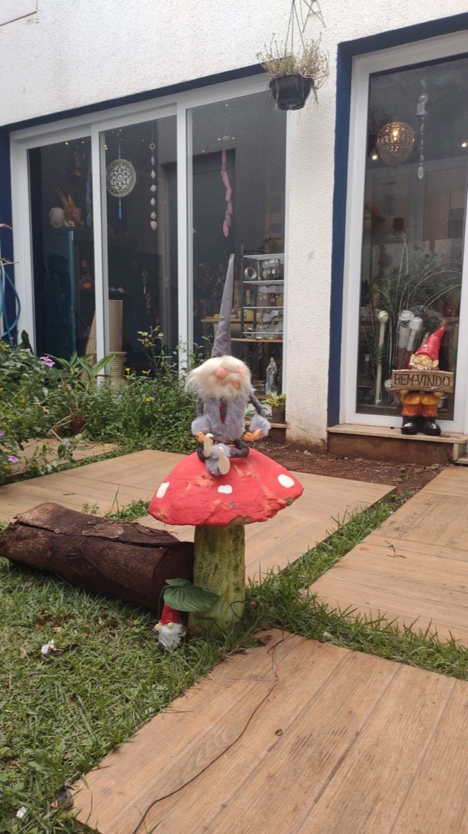 Jardim da entrada da loja, com gnomo sentado em um cogumelo vermelho