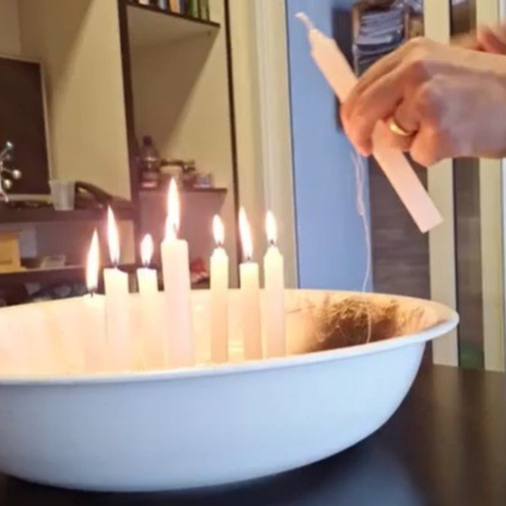 Velas brancas acesas em uma bacia durante um ritual