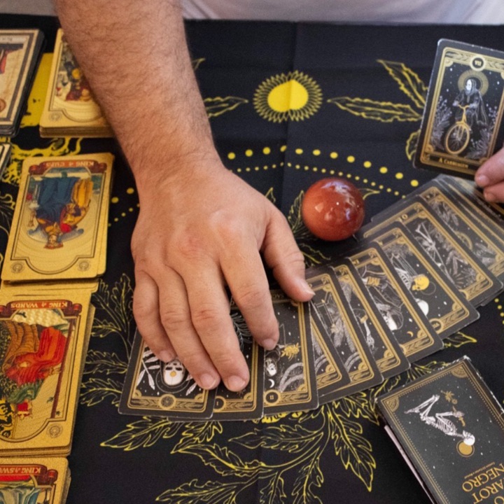 Cartas de tarot abertas sobre uma toalha preta com sol dourado
